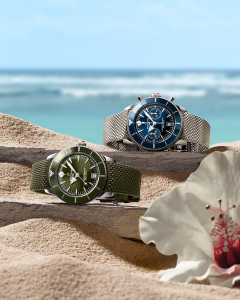 reloj verde y reloj azul de la coleccion breitling superocean heritage sobre la arena de la playa